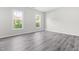 Bright bedroom features two windows for ample natural light, gray walls, and stylish laminate flooring at 5309 Neuse Wood Dr, Raleigh, NC 27616