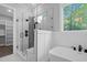 Bright bathroom featuring glass walk-in shower, modern fixtures, large tub, and backyard view at 5504 Earle Road, Raleigh, NC 27606