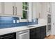 Modern kitchen boasts white quartz countertops, blue tile backsplash, stainless steel appliances, and bright natural light at 5504 Earle Road, Raleigh, NC 27606