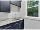 Laundry area featuring gray cabinets, stylish countertop, stainless steel sink and a window with natural light at 5504 Earle Road, Raleigh, NC 27606