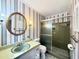 Bathroom featuring colorful wallpaper, decorative light fixture, and tiled shower with glass door at 5617 Partridge Ln, Raleigh, NC 27609