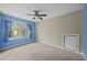 Cozy bedroom features bright blue walls, carpet, window with blue curtains, and a ceiling fan at 5617 Partridge Ln, Raleigh, NC 27609