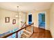 Upstairs hallway featuring hardwood floors, a chandelier, doorways, and artwork at 5617 Partridge Ln, Raleigh, NC 27609