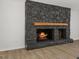 Stone fireplace with a wooden mantle and visible fire, adding warmth and character to the living space at 5709 Russell Rd, Durham, NC 27712