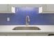 Close up of kitchen sink with blue backsplash and gold colored faucet at 5709 Russell Rd, Durham, NC 27712