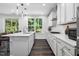 Contemporary white kitchen with hardwood flooring, white cabinets, stainless appliances, and an island sink at 7301 Villoria Ln, Raleigh, NC 27617