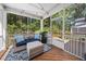 Inviting screened porch with wicker furniture, outdoor rug, and serene views of the surrounding wooded area at 7301 Villoria Ln, Raleigh, NC 27617