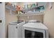 Bright laundry room with full-sized, white washer and dryer, plus storage shelves for organization at 80 Scarlet Bell Dr, Youngsville, NC 27596