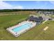 Aerial view of a community pool with lounge chairs and picnic tables surrounded by green space in a neighborhood at 80 Scarlet Bell Dr, Youngsville, NC 27596