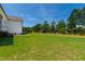 Expansive backyard with lush green grass, mature trees, and the side of the home at 808 Shiloh Hills Dr, Fuquay Varina, NC 27526