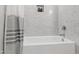 Clean bathroom featuring a white tub, gray tiled walls, and built-in niche for toiletries at 808 Shiloh Hills Dr, Fuquay Varina, NC 27526