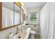 Well-lit bathroom featuring a sink vanity, framed mirror, toilet, and a window with privacy curtain at 905 Aversboro Rd, Garner, NC 27529