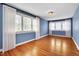 Light-filled bedroom with hardwood flooring, light blue walls, and large windows with white curtains at 1007 W Markham Ave, Durham, NC 27701