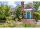 Charming brick home featuring beautiful landscaping and an inviting blue front door entrance at 1007 W Markham Ave, Durham, NC 27701