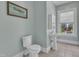 A bathroom featuring a pedestal sink, toilet, artwork, and large window at 118 N 7Th St, Smithfield, NC 27577