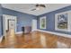 Large blue bedroom with hardwood floors, ceiling fan, and three windows at 118 N 7Th St, Smithfield, NC 27577