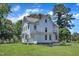 Rear view of the white home with an external staircase and lush lawn, showcasing the property's appeal at 118 N 7Th St, Smithfield, NC 27577