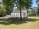 Angle shot of the home's exterior with a white deck and wheelchair ramp surrounded by mature trees and green grass at 119 Percheron Dr, Zebulon, NC 27597