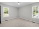 A sunlit bedroom with two windows, carpet, and neutral walls creating a serene atmosphere at 119 Percheron Dr, Zebulon, NC 27597