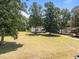 Spacious front yard view of a charming home nestled amongst mature trees on a sunny day at 119 Percheron Dr, Zebulon, NC 27597