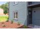 Close-up of an apartment building exterior with well-kept landscaping, showing the muted blue siding and black door at 1309 Hudson Ave # D6, Durham, NC 27705