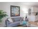 Living room with a gray sofa, artistic wall decor, and a view of the kitchen featuring white cabinets and modern appliances at 1309 Hudson Ave # D6, Durham, NC 27705