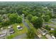 An aerial view showcases a tranquil neighborhood dotted with green trees and cozy homes on quiet roads at 1402 Tarleton Ave, Burlington, NC 27215