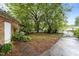 An overgrown backyard features mature trees, a brick exterior, and a concrete walkway at 1402 Tarleton Ave, Burlington, NC 27215