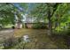 The backyard features mature trees and a brick exterior, but shows signs of drainage issues at 1402 Tarleton Ave, Burlington, NC 27215