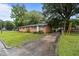 Charming one-story brick house with a well-manicured lawn, mature trees, and concrete driveway at 1402 Tarleton Ave, Burlington, NC 27215