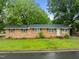 Charming brick ranch-style home with mature trees and a lush green lawn at 1402 Tarleton Ave, Burlington, NC 27215