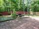 Backyard patio with a brick paver patio set, fire pit, and a red privacy fence in the background at 1487 Kentucky Ave, Sanford, NC 27332