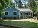 Charming home with blue siding, metal roof, white porch and landscaped yard surrounded by mature trees at 1487 Kentucky Ave, Sanford, NC 27332