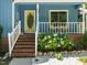 Inviting porch featuring a yellow front door, white railings, and colorful flower landscaping around the brick base at 1487 Kentucky Ave, Sanford, NC 27332