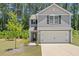 Charming two-story home with a gray exterior, a manicured lawn, and a young tree in the front yard at 150 Ivy Bank Dr, Angier, NC 27501