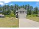 Two-story home with gray siding, a well-maintained lawn, and a long driveway leading to an attached garage at 150 Ivy Bank Dr, Angier, NC 27501