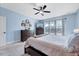 Bedroom with blue walls, white carpet, large window view, ceiling fan, and TV on dresser at 1624 Struble Cir, Willow Springs, NC 27592