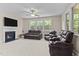 The living room with a fireplace, ceiling fan, and large windows with lots of natural light at 2120 Rainy Lake St, Wake Forest, NC 27587