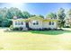 Charming ranch style home with well-manicured lawn, mature trees, and an American flag on the front porch at 233 Pressly Foushee Rd, Sanford, NC 27330