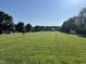 Expansive green space with community recreational amenities, featuring mature trees and landscaping at 305 Wallington Ct, Mebane, NC 27302