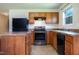 Well-lit kitchen with wooden cabinetry, black appliances, and laminate countertops, ready for culinary adventures at 305 Wallington Ct, Mebane, NC 27302