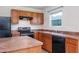 Well-lit kitchen with wooden cabinetry, black appliances, and laminate countertops, ready for culinary adventures at 305 Wallington Ct, Mebane, NC 27302