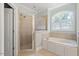 Inviting bathroom showcasing a shower, soaking tub, and arched window, providing a relaxing and stylish experience at 312 Flint Point Ln, Holly Springs, NC 27540