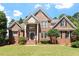 Beautiful two-story brick home with manicured lawn, mature trees, and classic architectural detailing at 312 Flint Point Ln, Holly Springs, NC 27540
