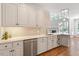 Bright kitchen featuring white cabinetry, stainless steel appliances, and a view into a naturally-lit living space at 312 Flint Point Ln, Holly Springs, NC 27540