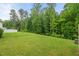 Serene backyard featuring a lush lawn and mature trees, offering a private outdoor space at 3215 Retama, New Hill, NC 27562