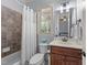 Cozy bathroom with a tub/shower, tiled accent wall, wood vanity, and window overlooking outdoors at 3306 Storybook Ln, Raleigh, NC 27614