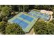 Overhead view of blue and green tennis courts surrounded by fencing and mature trees at 3306 Storybook Ln, Raleigh, NC 27614