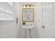 Bright bathroom featuring pedestal sink, gold fixtures, mirror, and natural light at 3317 Harden Rd, Raleigh, NC 27607