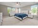 Bright bedroom features two windows with blue accents, neutral carpet, and a decorative white headboard at 35 Clubhouse Dr, Youngsville, NC 27596